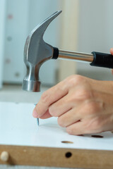 man using hammer hammering a nail into wooden boards, assembling or repairing furniture at home. DIY, Renovation, repairing and development home or apartment concepts
