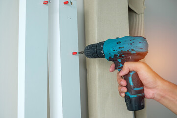 man using a cordless screwdriver assembling furniture at home, Carpenter working with electric screwdriver on the work