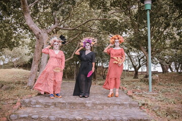 Obraz premium Group portrait of three women with the makeup of the catrinas.. Makeup for the celebration of Day of the Dead in Mexico. Outdoors portrait.