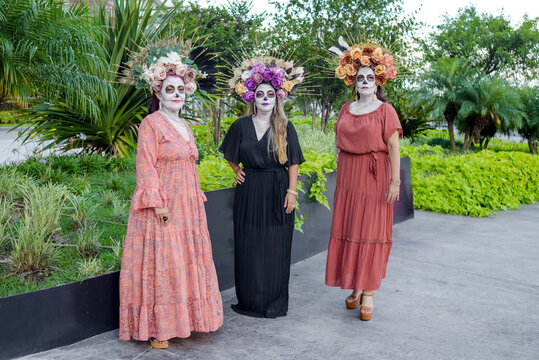 Group portrait of three women with the makeup of the catrinas.. Makeup for the celebration of Day of the Dead in Mexico. Outdoors portrait.