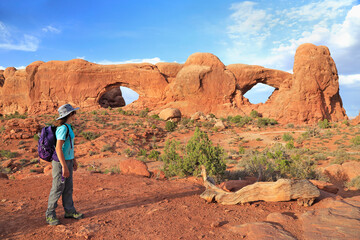 Young girl tourist admiring South and North Windows in Arches National Park, Utah, USA