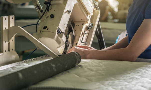 Woman in the process of sewing on professional equipment. Sewing fabric in production