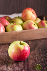 Ripe whole apple on the background of a fruit box on a wooden table. Local seasonal fruits. Vertical