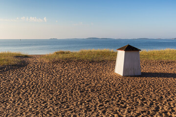 Wooden changing booth or hut at the empty and sandy Tulliniemi beach in Hanko, Finland, at a sunny morning in the summer.