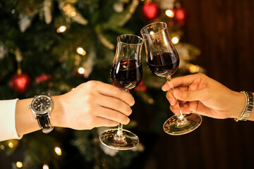 Couple celebrating by drinking red wine, she and him, clinking wine glasses, elegant dining background. Celebrate Christmas and New Year's Day