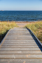 Wooden boardwalk leading to an empty beach in Hanko, Finland, on a sunny day in the summer. Focus on the front, shallow depth of field.