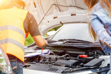 Closeup and crop motor vehicle mechanic checking engine oil to record the repair history with sun and lens flare background.