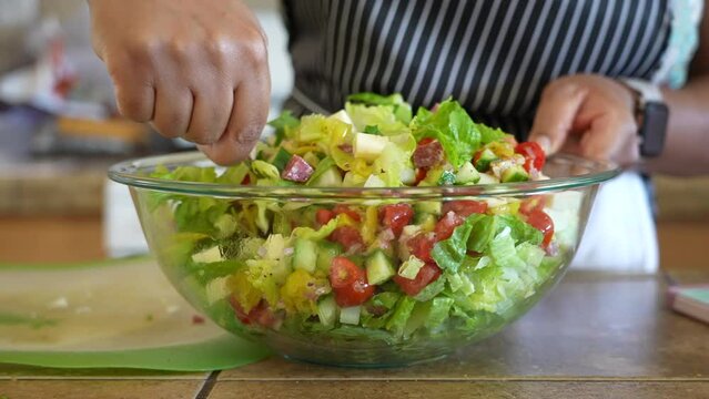 Mixing a antipasto salad in a large glass bowl - series