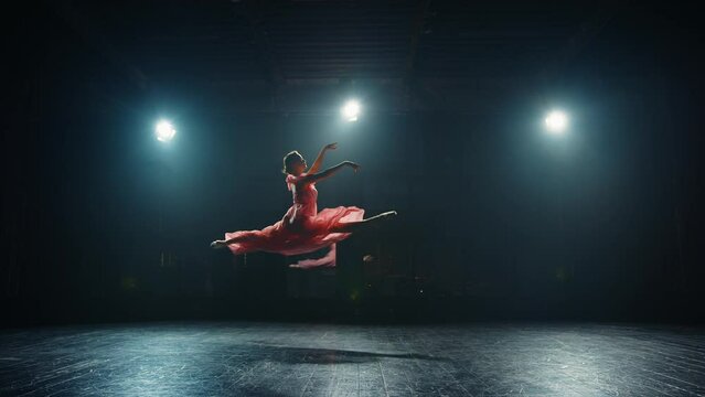 Young graceful classical ballet female dancer in tutu is performing choreography on stage. Ballerina makes difficult pirouette on stage