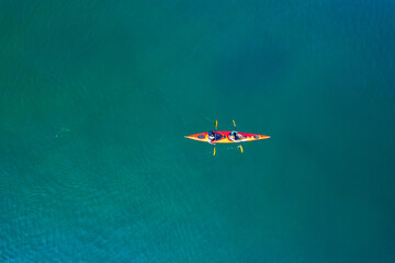 Red kayak boat two rowers on blue turquoise water sea, sunny day. Concept teamwork for business...