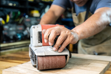 carpenter working with belt sander polishing on wooden in workshop ,DIY maker and woodworking concept. selective focus - Powered by Adobe