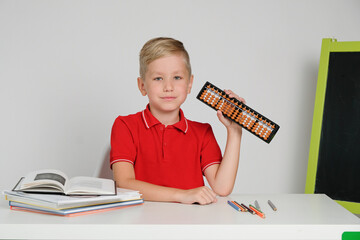 Cute school boy doing simple math exercises with abacus scores. Math and mental arithmeric.