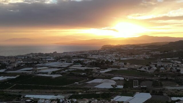 beautiful sunset with camera dropping down and a party cloudy sky with the sea on the left and countryside on the right.