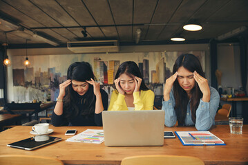 Fototapeta na wymiar Stressed businesspeople, Frustrated and upset in business pressure and overworked at office. Group of Adult Asian woman working on laptop, feeling tire and headache. Stressed and Frustrated concept.
