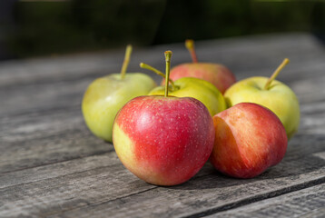 Red and green apples on a wooden table close-up.