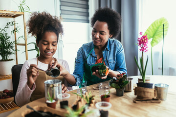 Mother and daughter planting at home, spending time together and having fun.