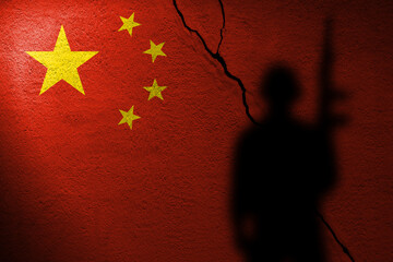 Flag of China painted on a cracked wall with soldier shadow