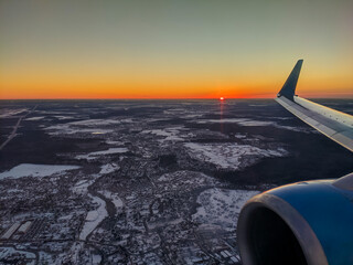 Moscow, Russia - March 01, 2022: View at dawn from the window on the wing of an airplane flying over snowy Moscow