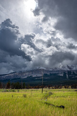 Sun bursting through the clouds above a meadow and mountains near the Jasper Airfield in Jasper National Park, Alberta