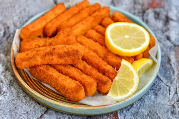 Close up of   Crispy breaded  deep fried fish fingers with breadcrumbs served  with remoulade sauce and  lemon Cod Fish Nuggets on rustic wood table background