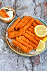 Close up of   Crispy breaded  deep fried fish fingers with breadcrumbs served  with remoulade sauce and  lemon Cod Fish Nuggets on rustic wood table background
