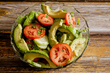 Vegetable salad in a glass bowl on a wooden table. Vegetables, healthy food.
