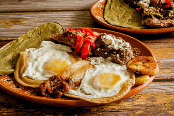Huevos rancheros, meat, beans, nopal and fried plantains in a clay dish. Typical Mexican food.