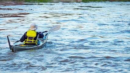 man wearing life jacket Sailing a small boat in the middle of the river.