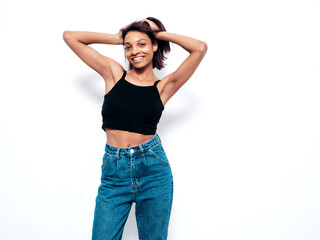 Portrait of young beautiful black woman. Smiling model dressed in summer jeans clothes. Sexy carefree female posing near wall in studio. Tanned and cheerful
