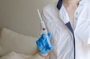 A medical worker in a dressing gown holds a syringe with medicine. Injection. Medical device. Covid-19. Pandemic. Medicines for illness. Tablets and capsules in hand. anabolic drugs.