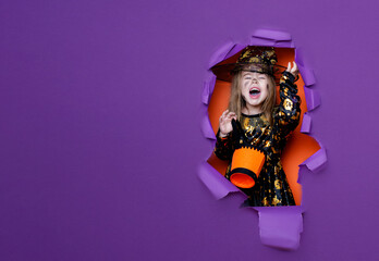 Laughing funny child girl in a witch costume in halloween - obrazy, fototapety, plakaty