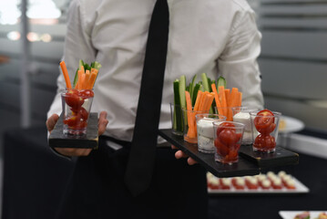 The waiter offers snacks consisting of various different vegetables at the party