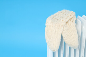 Modern electric heater with knitted socks on blue background