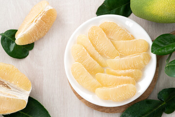 Fresh pomelo fruit on bright wooden table background.