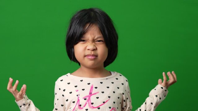 Portrait of Asian angry and sad little girl on green screen background, The emotion of a child when tantrum and mad, expression grumpy emotion. Kid emotional control concept