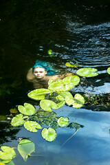 magical sexy young seductive fairytale mermaid woman with blue hair swimming in the river water...