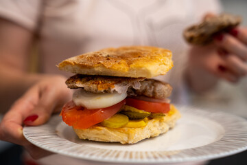 woman hand holding home made sandwich with meat, onion, tomato, cucumber and cheese, perfect bokeh 