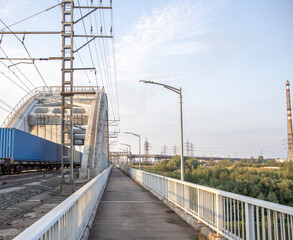 Fototapeta na wymiar Freight train rides on the railway bridge. Industrial Zone.
