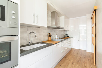 Modern white kitchen with wood flooring. Cabinet handles are protected with a soft sponge to protect a child.