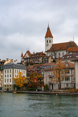 Fototapeta na wymiar Nice view along Aare lake and Stadtkirche in old town of Thun during autumn , winter cloudy day : Thun , Switzerland : December 2 , 2019