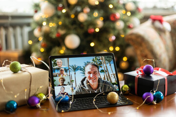 Young smiling man sitting on sofa at home and using digital tablet while relaxing in the cozy of his home.