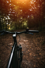 Fototapeta na wymiar Bicycle frame, air suspension fork and handlebar with brake handle with forest background. Concept of using MTB on a path in the woods.
