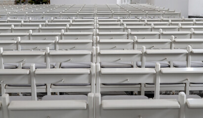 Many empty white benches stand in rows one behind the other as a background