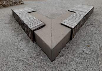 a bench made of one piece of V-shaped concrete. a park bench in the shape of an arrow as a mirrored...