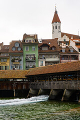 Beautiful view , medieval buildings , Aare lake and wooden bridge in old town of Thun during autumn , winter cloudy day : Thun , Switzerland : December 2 , 2019