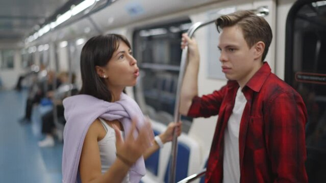 A couple rides on the subway, stand, hold on to the handrail, swear, talk, shout. Slow motion 120fps footage