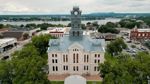Aerial flyover. Medium speed. close flyover clock courthouse. Granbury lake reveal. Flyover Granbury Square. Hood County TX. 4k_24fps. Cars driving included. Comanche Peak reveal. Cloudy overcast.
