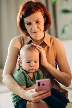 Mom with baby watching to smart mobile phone videos or work text