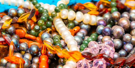 Beads and necklaces made of colored semi precious stones. Background from a variety of beautiful jewelry, multi-colored turquoise stones, amber, cat's eye, pearls.