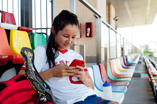 Smiling Player Text Messaging Using Smart Phone At Stadium